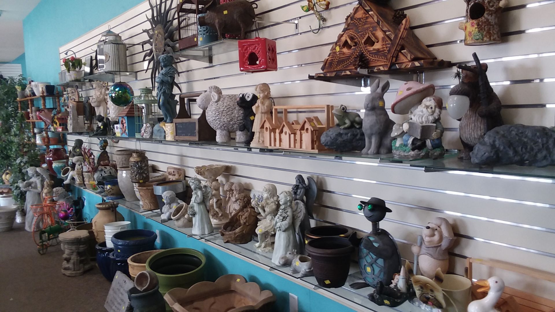 A shelf of ceramic and concrete lawn ornaments and animal statues.