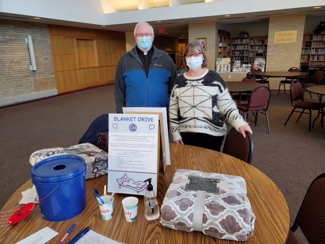 Two volunteers standing behind a table for a blanket drive.