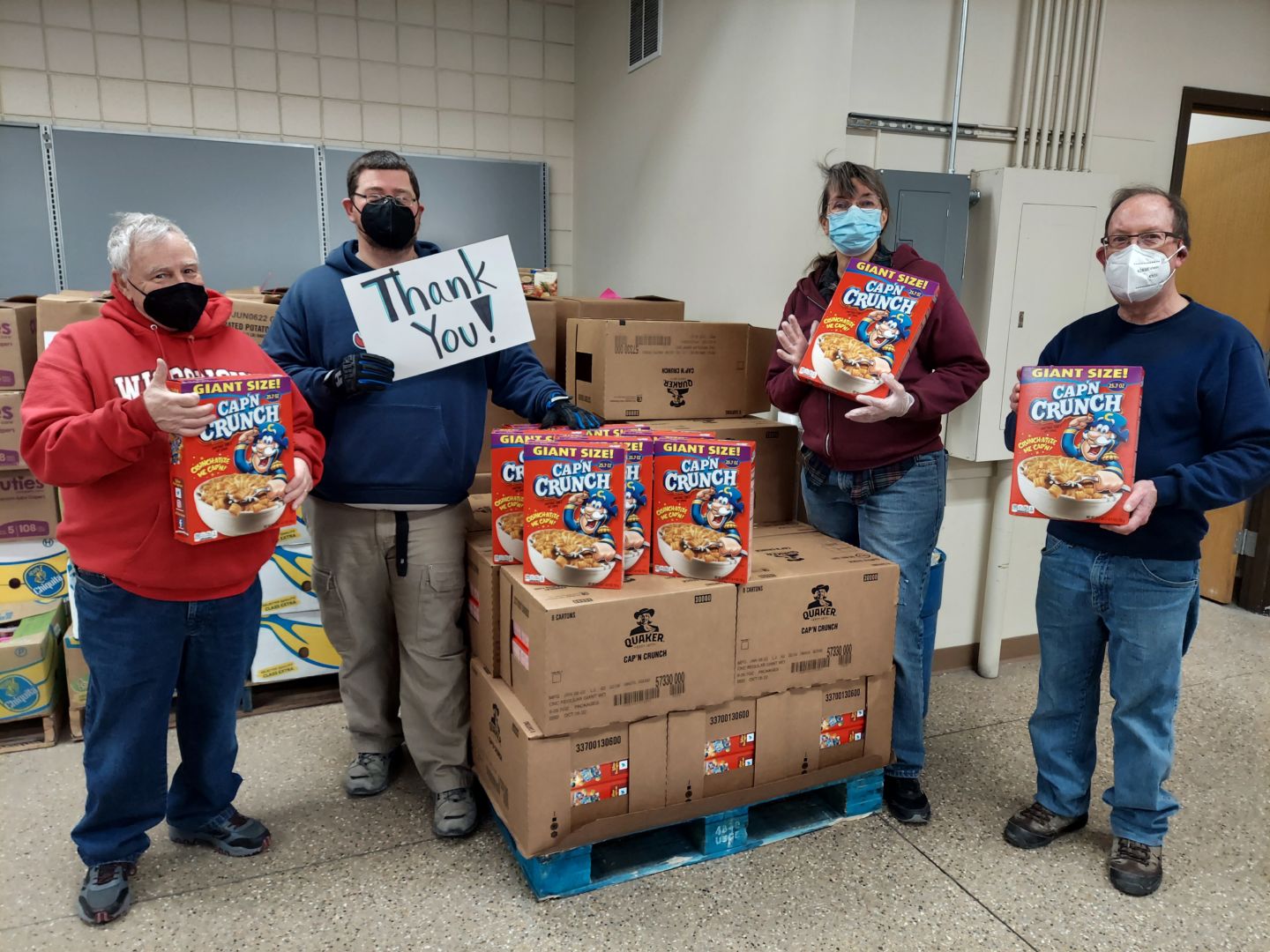 Four volunteers and staff standing buy a pallet full of Cap'n Crunch cereal boxes, holding a sign which reads, "Thank you!"