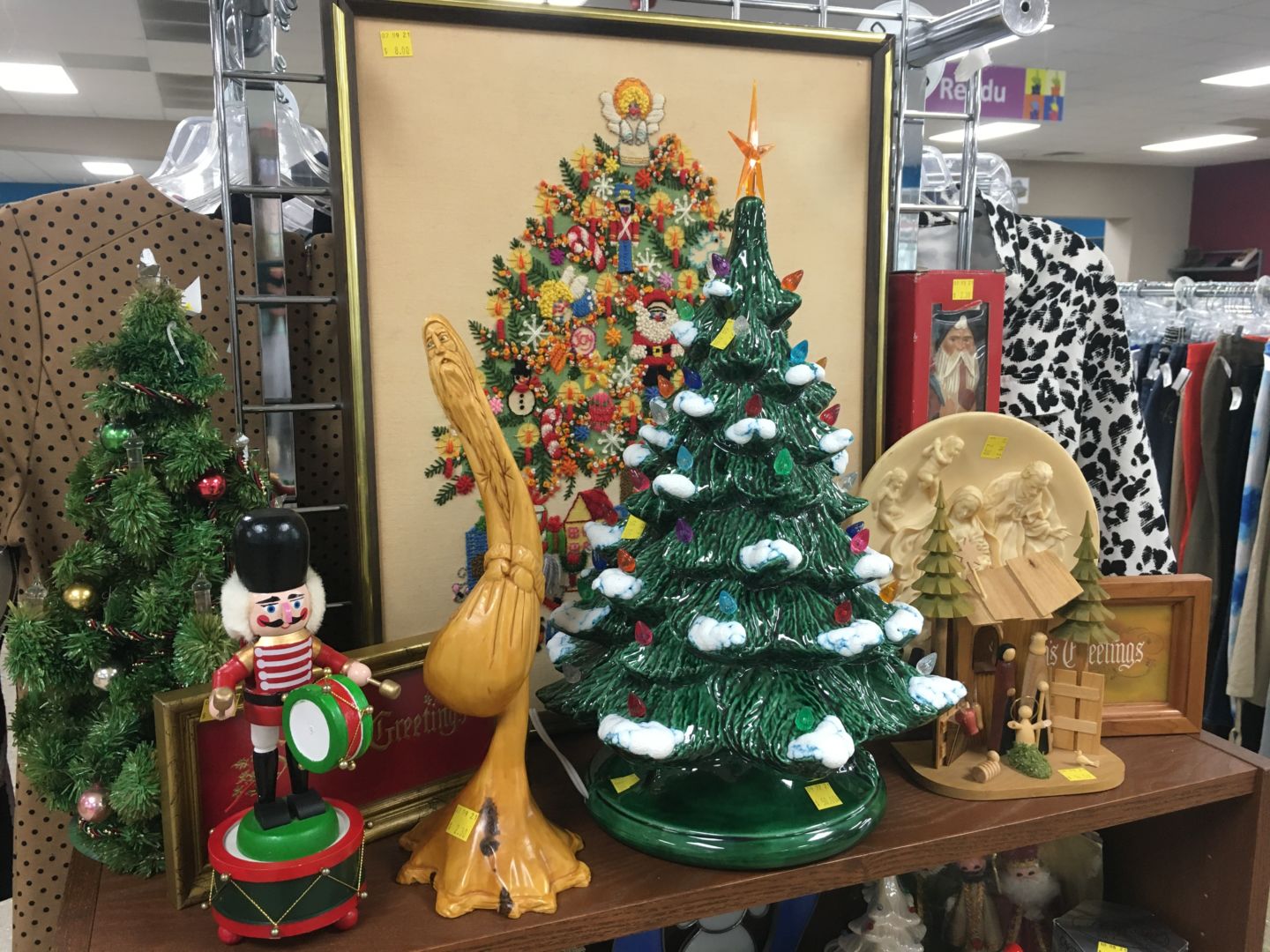 A collection of vintage/collectible Christmas décor. There is a picture of a Christmas tree and two ceramic trees, a small nutcracker, and a Santa Clause figurine.